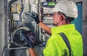 Protección dieléctrica contra riesgos eléctricos Trabajador con casco y guantes de seguridad, operando en un cuadro eléctrico, que representa la protección dieléctrica del calzado contra riesgos eléctricos.