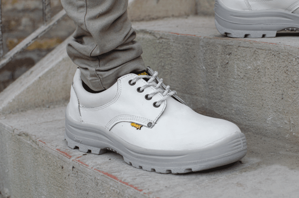 Zapato de seguridad GamaX, modelo 102A-1112P, en cuero flor color blanco con suela gris, en uso.