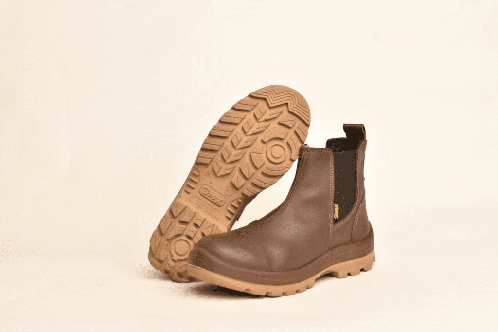 Par de botines de seguridad elásticos GamaX, modelo 108A-118P, en color marrón, con un botín mostrando la suela de protección antideslizante en tono claro.