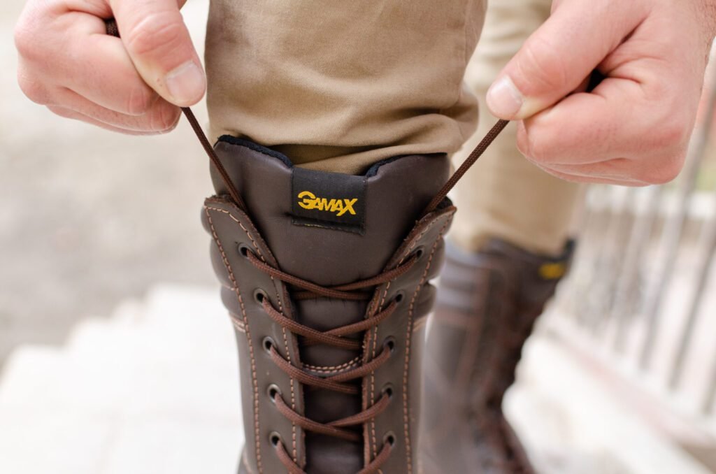 Detalle de los cordones marrones ajustándose en un borceguí de seguridad GamaX, resaltando el logo y la comodidad.