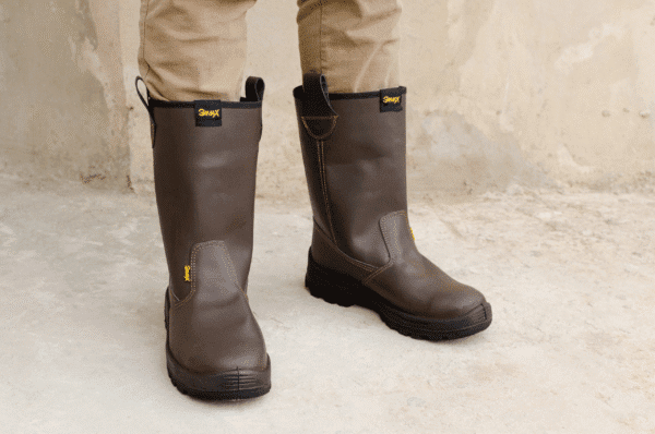 Hombre usando un par de botines de seguridad GamaX, modelo 400A-400P, en color marrón, con pantalón de trabajo color beige.